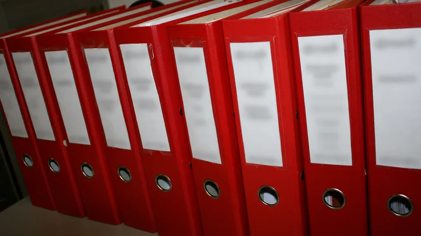Red accounting archive binders with blurred labels, illustrating organised audit records
