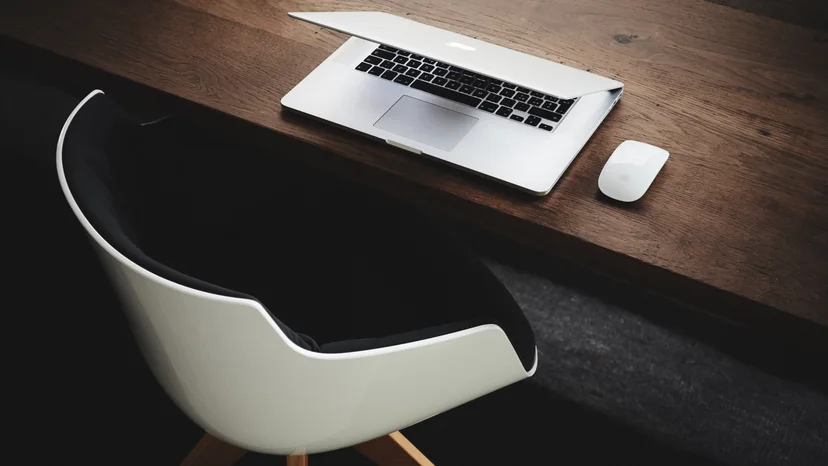 A laptop and mouse on a wooden office desk, illustrating an external accounting workspace