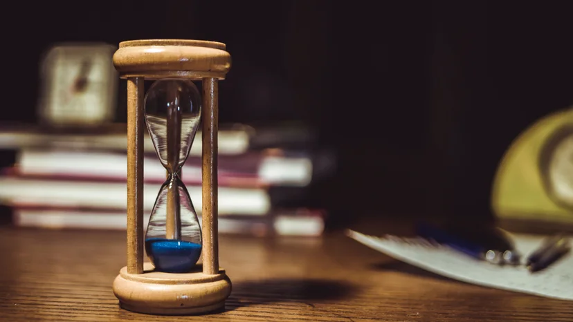 A wooden hourglass with blue sand on a desk, illustrating tax response deadlines