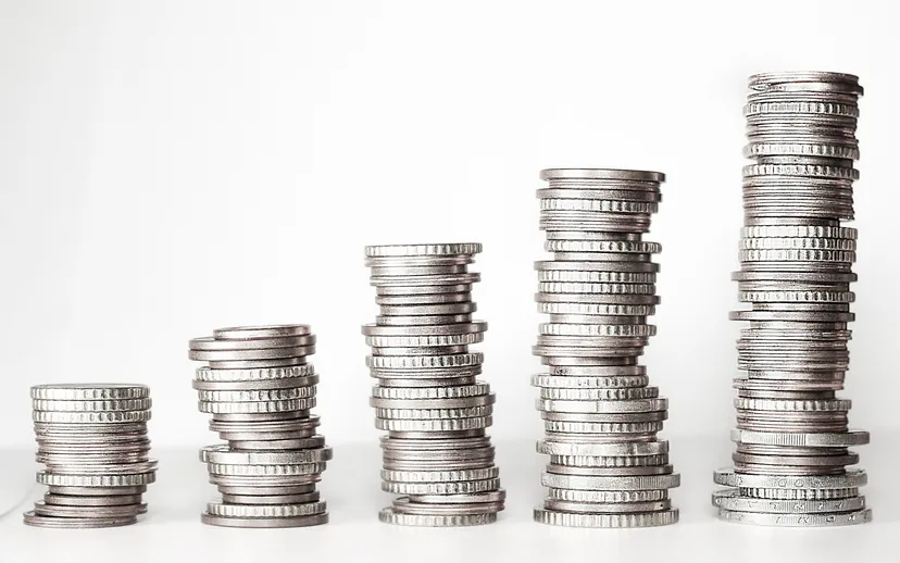 Five stacks of silver coins rising in height from left to right against a white background.