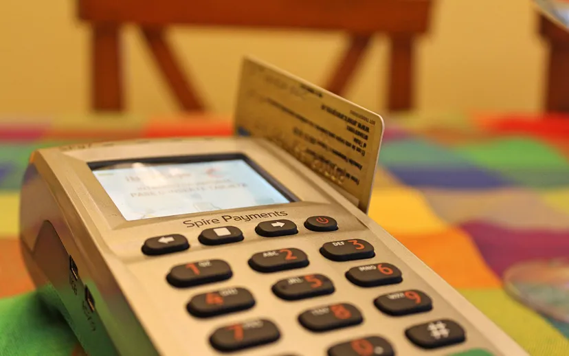 A hand using a card payment terminal at a shop counter