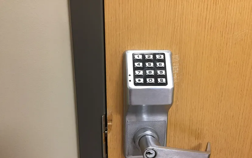 A keypad code lock fitted on a wooden office door.