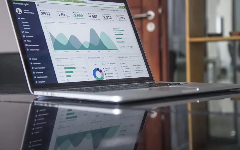 A laptop on a desk showing a business dashboard with figures and charts.