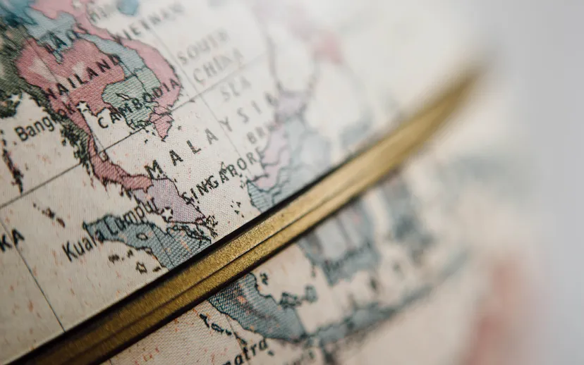 Close-up of a world globe with a golden equator line across Southeast Asia.