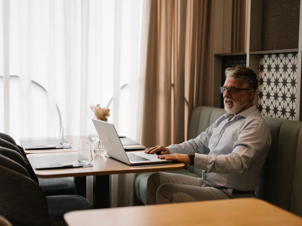 A man working on a laptop at a table in a quiet office lounge