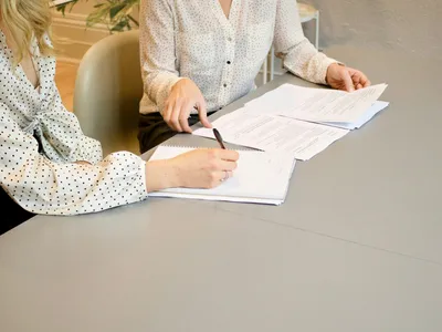 Two colleagues going through printed documents at a meeting table
