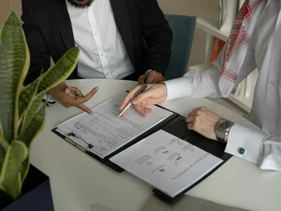 Two businessmen reviewing and signing company documents