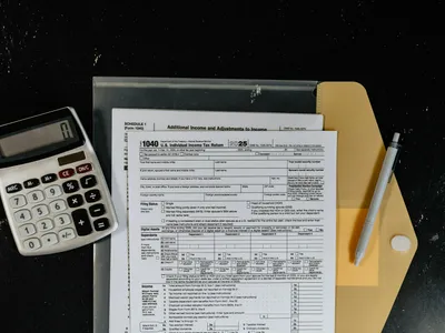 Tax forms with a calculator and a pen on a desk